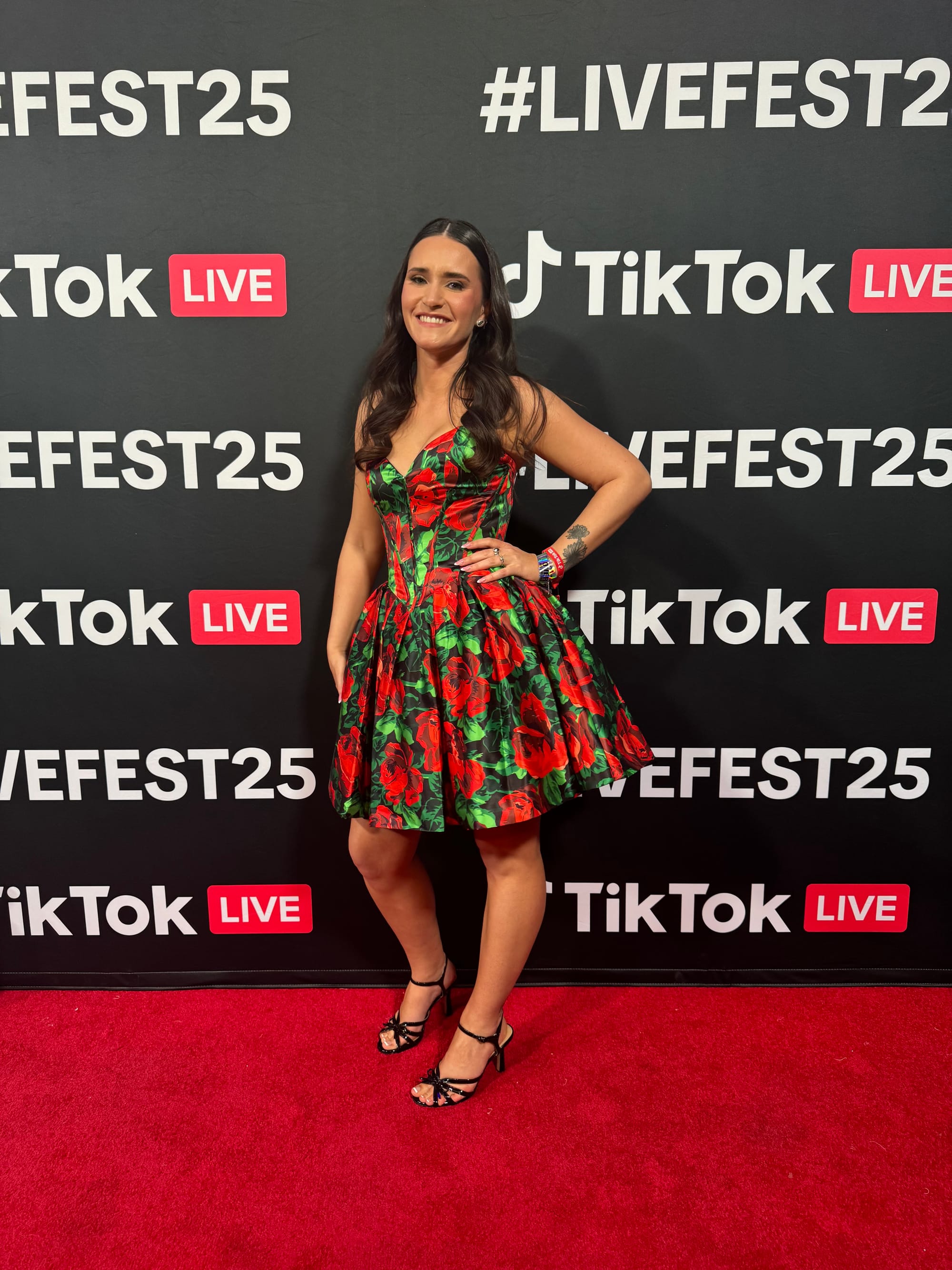 Sarah Soda on the red carpet at TikTok LiveFest 2025 wearing a red rose-print dress